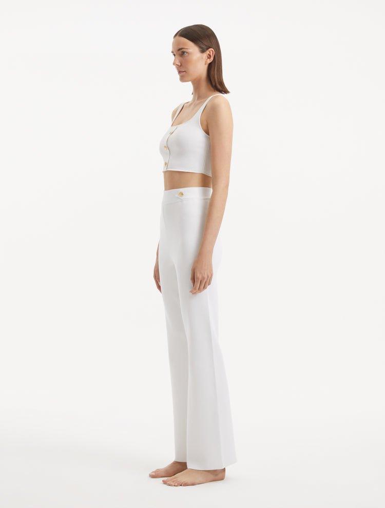 "Model wearing the Moira White Pants from the side, illustrating the wide-leg cut and the flattering high-waisted fit."