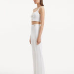 "Model wearing the Moira White Pants from the side, illustrating the wide-leg cut and the flattering high-waisted fit."