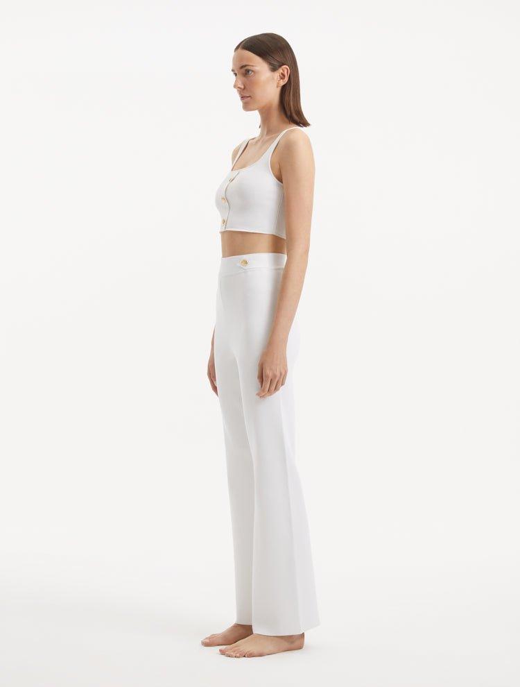 "Model wearing the Moira White Pants from the side, illustrating the wide-leg cut and the flattering high-waisted fit."