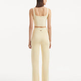 "Model wearing the Moira Yellow Pants from the back, focusing on the smooth, high-waisted style and wide-leg silhouette. "