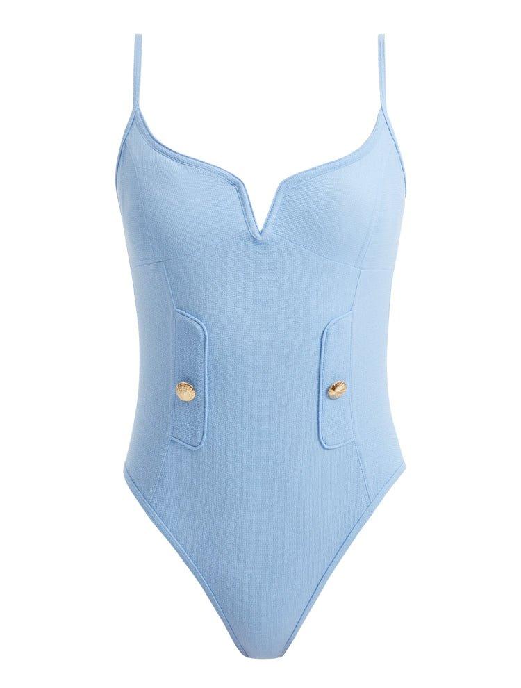 Artistic depiction of the Muriel Baby Blue Swimsuit, highlighting its graceful V-shape detail, elegant shell button accents, and luxurious Italian fabric in a beautifully stylized composition.
