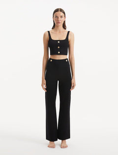 "Model wearing the Murphy Black Top from the front, showcasing the hand-knitted texture, deep black color, and exquisite shell-shaped gold buttons. "