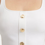 "Close-up view of the Murphy White Top, highlighting the intricate hand-knitted texture and shell-shaped gold buttons. "