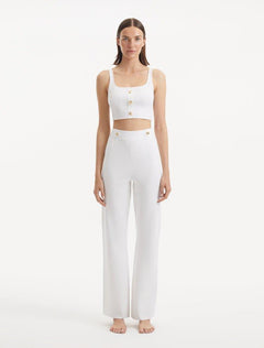 "Model showcasing the Murphy White Top and Moira Pants from the front, focusing on the hand-knitted texture, pristine white color, and shell-shaped gold buttons. "