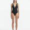 Model wearing the Naida Black Swimsuit, showcasing the elegant V-neck design and shell-shaped gold buttons.