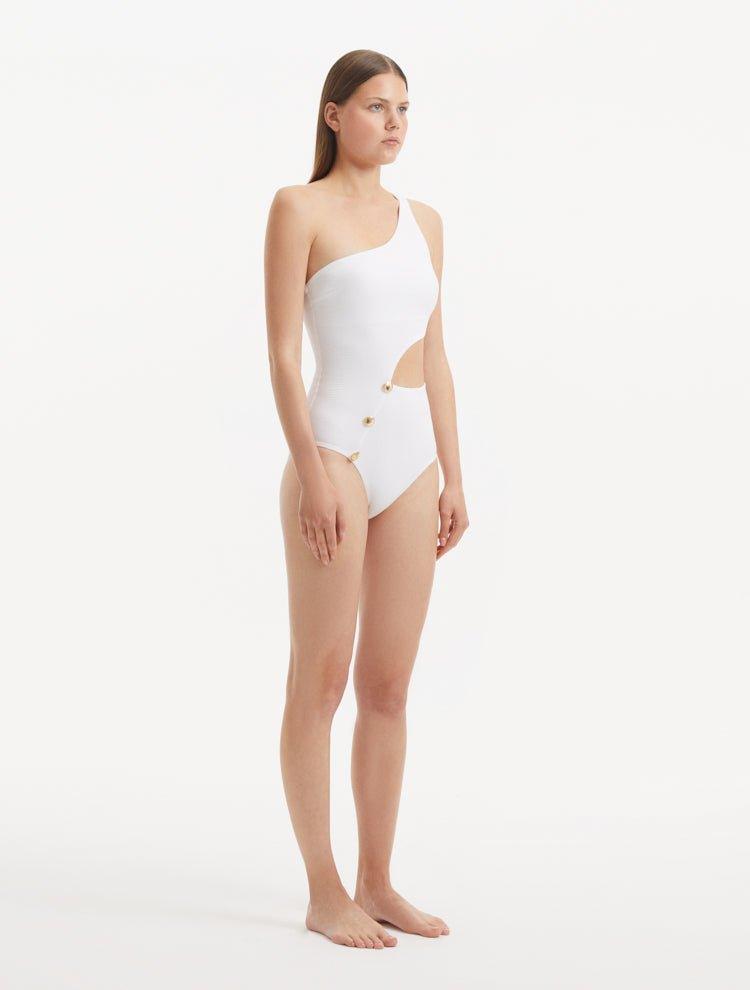 Side profile of the Narella White Swimsuit, illustrating the modern cutout and sophisticated one-shoulder silhouette.