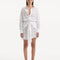 "Model wearing the Nayeli White Dress from the front, showcasing the broderie anglaise fabric, button front, and self-tie waist."