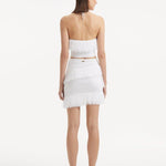 "Model displaying the Nebula White Knit Top from the back, focusing on the clean lines and tie-neck detail. "