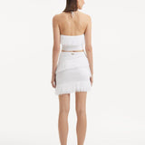 "Model displaying the Nebula White Knit Top from the back, focusing on the clean lines and tie-neck detail. "