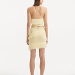 "Model displaying the Nebula Yellow Top and Arlo Yellow Skirt from the back, emphasizing the smooth, clean lines and tie-neck detail. "