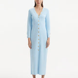 "Model wearing the Nira Baby Blue Dress from the front, highlighting the elegant V-neckline, unique shell-shaped gold buttons, and the luxurious knit fabric. "