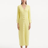 "Model wearing the Nira Yellow Dress from the front, highlighting the vibrant yellow color, elegant V-neckline, and shell-shaped gold buttons. "