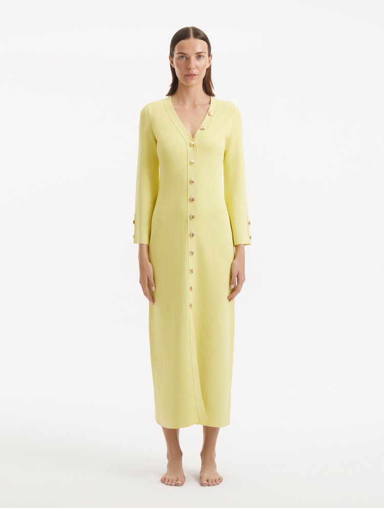 "Model wearing the Nira Yellow Dress from the front, highlighting the vibrant yellow color, elegant V-neckline, and shell-shaped gold buttons. "