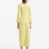 "Model showcasing the Nira Yellow Dress from the back, emphasizing the flowing, ankle-length design and the bright yellow hue. "