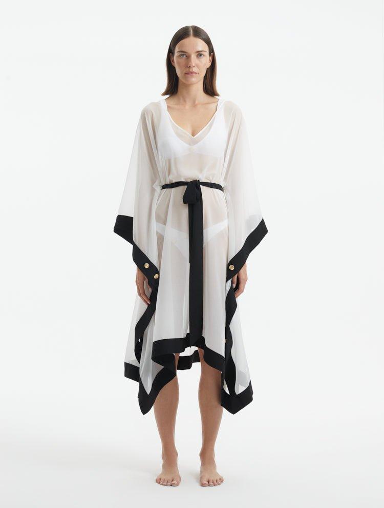 "Model wearing the Opal White Caftan from the front, showcasing the V neckline, knee-length design, and self-tie belt."