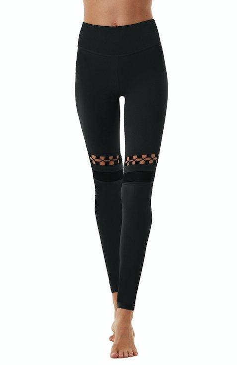  "Orla Black Leggings back view, displaying the mesh and cut-out panel design. The leggings offer a stylish and functional look with a stretchable fit."