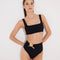 Front View: Model in Patrizia Black Bikini Bottom - MOEVA Luxury Swimwear, High-Waist, Cut-out Detail, Gold Sculpted Hoop Accessory, Moderate Bottom Coverage, MOEVA Luxury Swimwear  