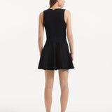"Model displaying the Rayan Black Dress from the back, focusing on the smooth knit texture and the thigh-length cut."