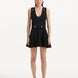 "Model wearing the Rayan Black Dress from the front, highlighting the meticulous knitted fabric, the midnight black color, and the shell-shaped gold buttons. "