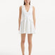 "Model wearing the Rayan White Dress from the front, showcasing the pure white knitted fabric, the V-neckline, and the shell-shaped gold buttons."