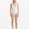 Model showcasing the Reva White Swimsuit, highlighting the scoop neckline and shell-shaped gold buttons.