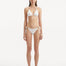 Rhea White Bikini Top showcasing the sleek, minimalist design and gold sculpted accessory.