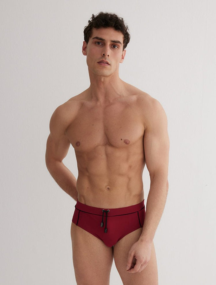 Front View: Model in Ricardo Bordeaux/Black Briefs - MOEVA Luxury Swimwear, Duo/Tri-Colored, Elasticated Waistband, Strechy Fabric, Tie at the Front, Quick Dry, Comfortable Fit, MOEVA Luxury Swimwear
