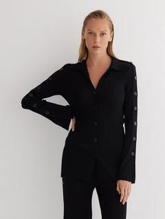Front View: Model in Salome Black Shirt - MOEVA Luxury Swimwear, Knitted Shirt, Long Sleeved, Button Details Along Sleeves and Front, Close Fit, MOEVA Luxury Swimwear