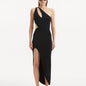 "Model showcasing the Shore Black Dress from the front, highlighting its sleek black hue, one-shoulder design, and daring slash cut-out detail. "