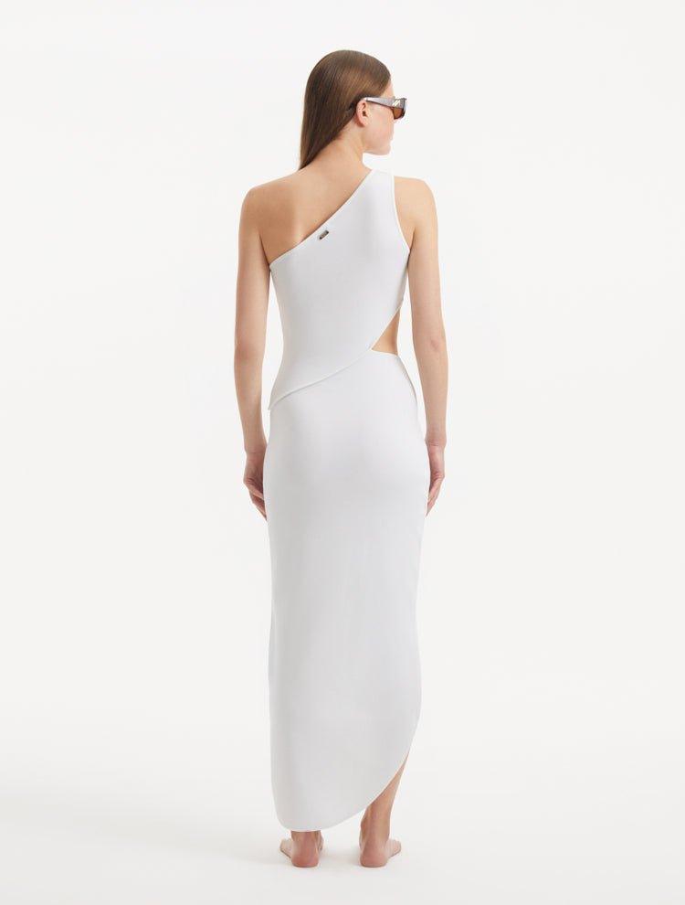 "Model displaying the Shore White Dress from the back, emphasizing the asymmetric one-shoulder design and the elegant side slit that enhances the flowing silhouette."