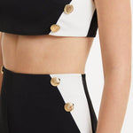 "Close-up view of the Wade Black/White Pants, detailing the shell-shaped gold buttons and the contrasting black and white fabric, highlighting the intricate design elements and luxurious accents."