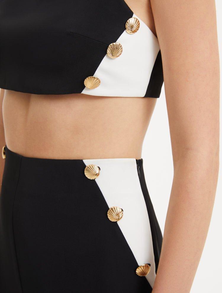 "Close-up view of the Wade Black/White Pants, detailing the shell-shaped gold buttons and the contrasting black and white fabric, highlighting the intricate design elements and luxurious accents."