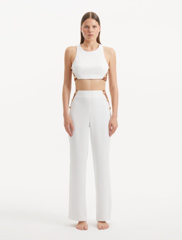 "Model showcasing the Wade White/Brown Pants from the front, highlighting the high-waist design, the contrasting white and brown colors, and the elegant shell-shaped gold buttons."